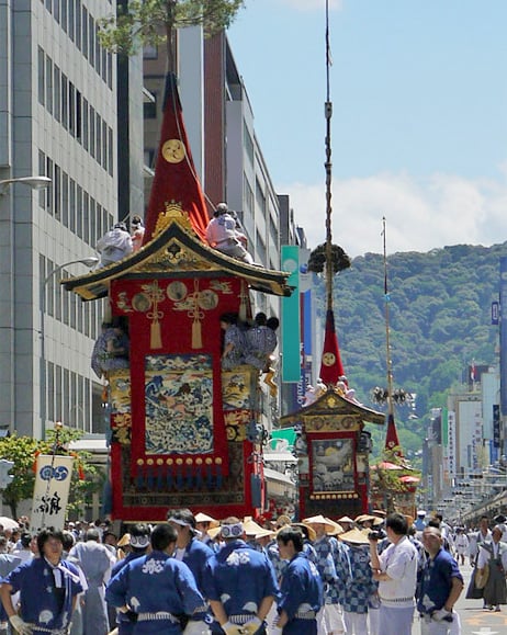 写真:青い法被姿の人達が山鉾を引いて街中を練り歩いている様子